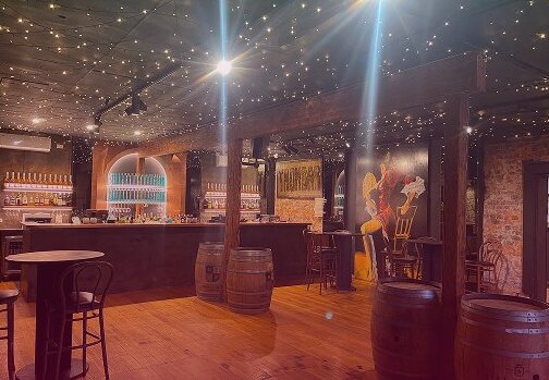 The Trombar dining room with timber floors, wine barrel tables and a ceiling of fairy lights